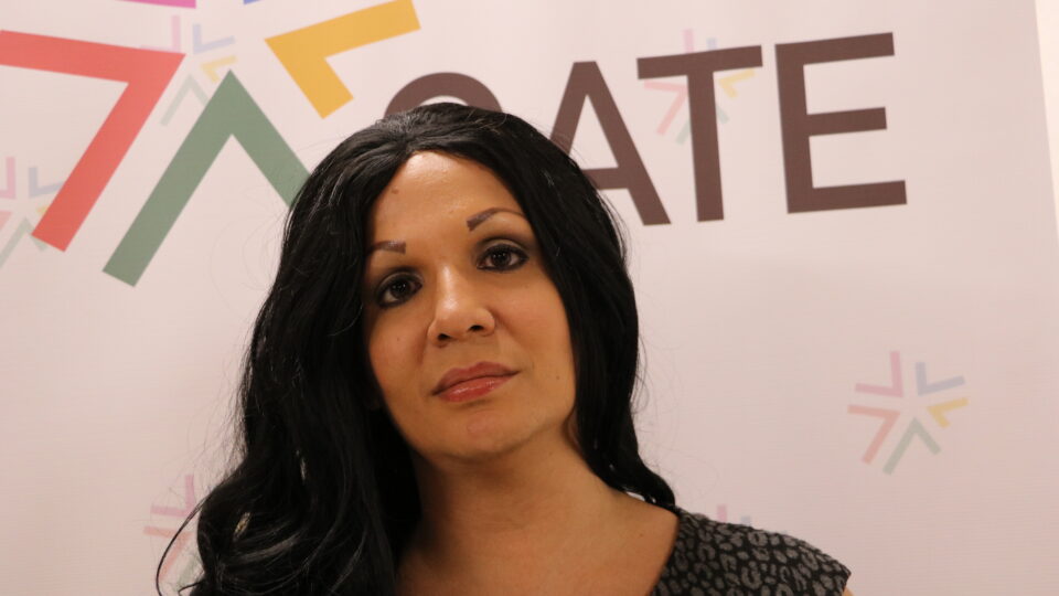 Latina woman looking into the camera with long black hair on a white background with GATE's logo