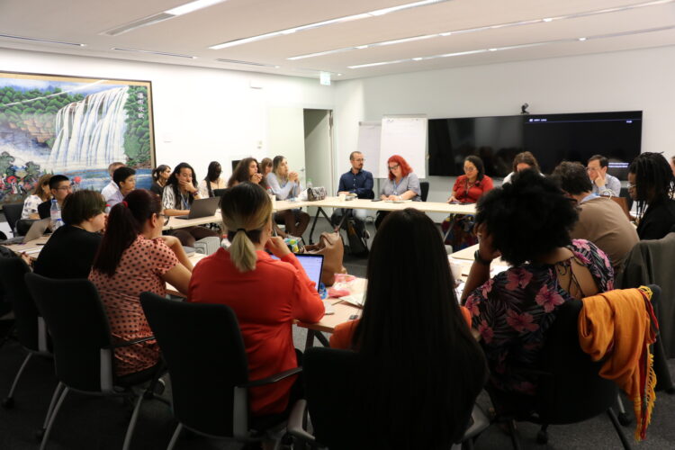 Wide angle picture of trans activists sitting around a large room in discussion with UNAIDS staff