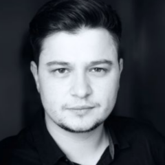 Patrick Braila monochrome headshot, looking into the camera against a black background