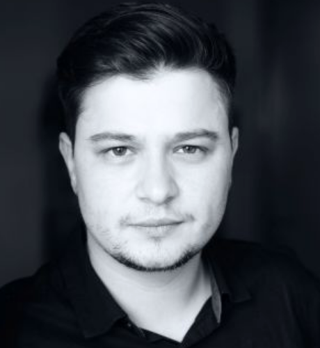 Patrick Braila monochrome headshot, looking into the camera against a black background