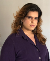 Kira Xonorika profile picture, looking into the camera wearing a black blouse with long brown hair