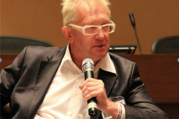Photo of Sam Winter seated, speaking into a microphone
