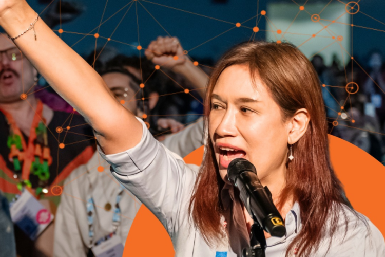 A trans woman holds her fist up in the air while speaking into a microphone